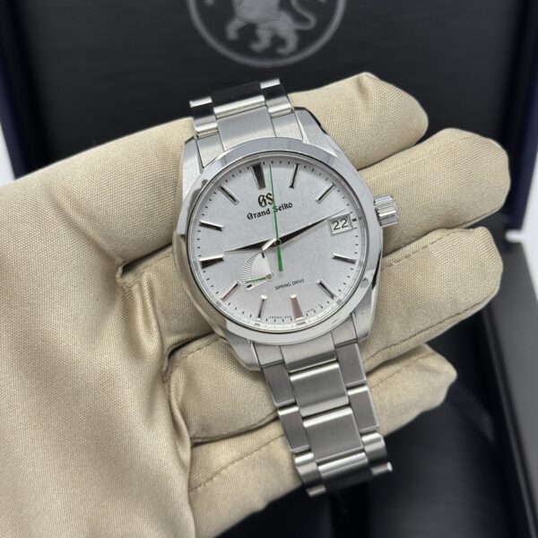 Grand Seiko SBGA427 Spring Drive wristwatch with silver dial, power reserve indicator, and green seconds hand, shown in a gloved hand