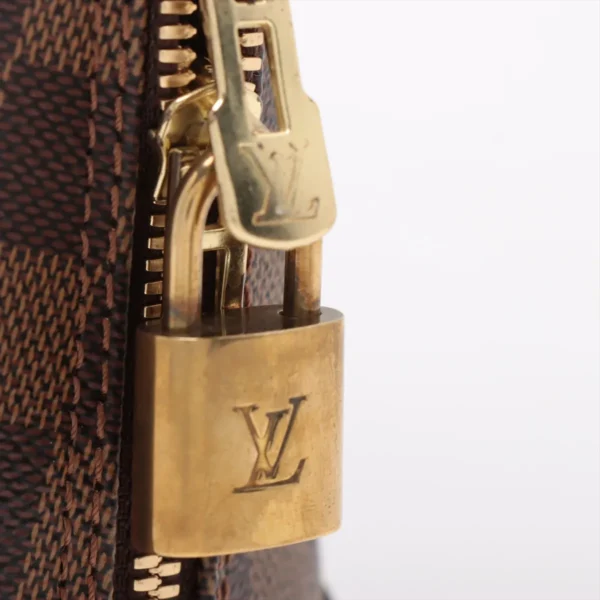 Macro shot of the gold-tone LV padlock and zipper pull attached to the Damier Ebene canvas.