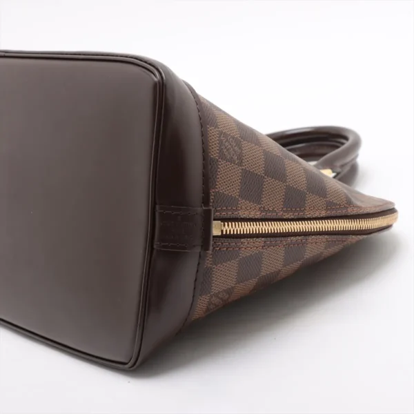 Side view of the Alma PM showing the structured bottom and brown leather trim with zipper placement.
