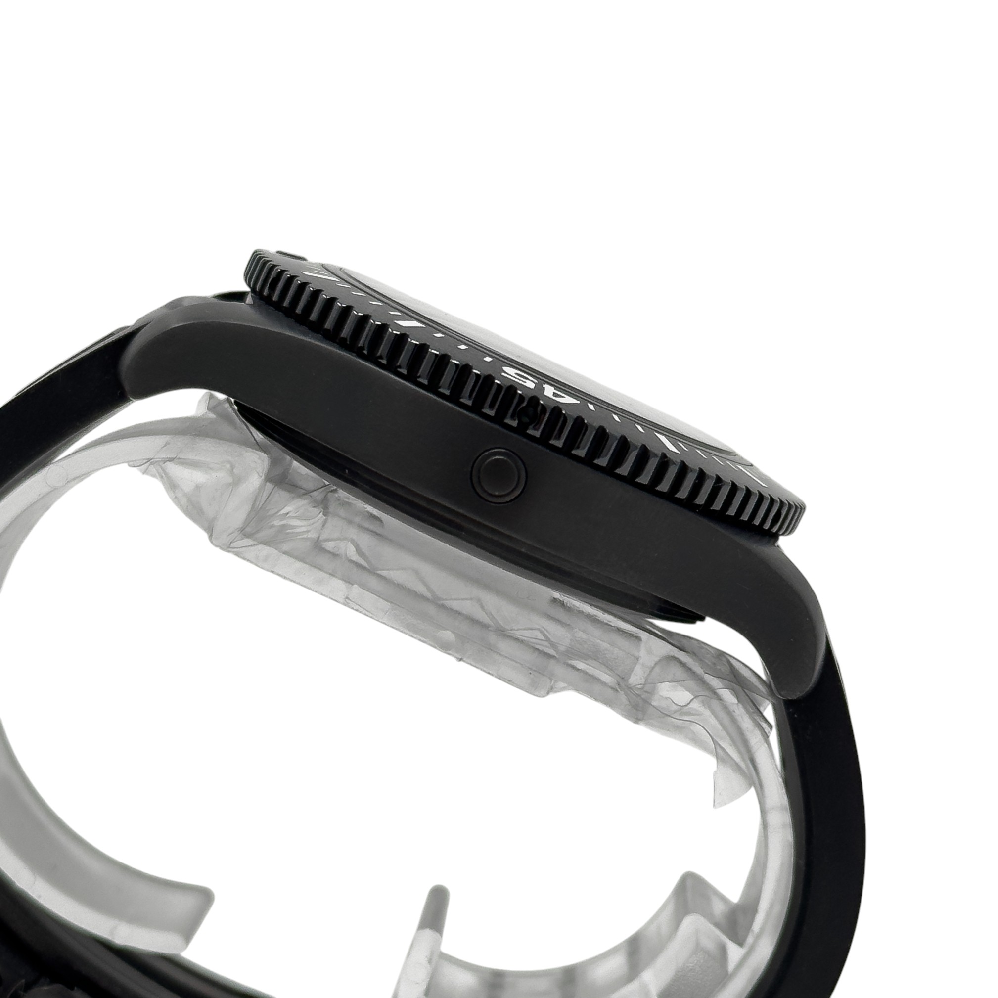 Close-up side view of a black watch case and serrated rotating bezel with part of the strap and clear protective plastic visible