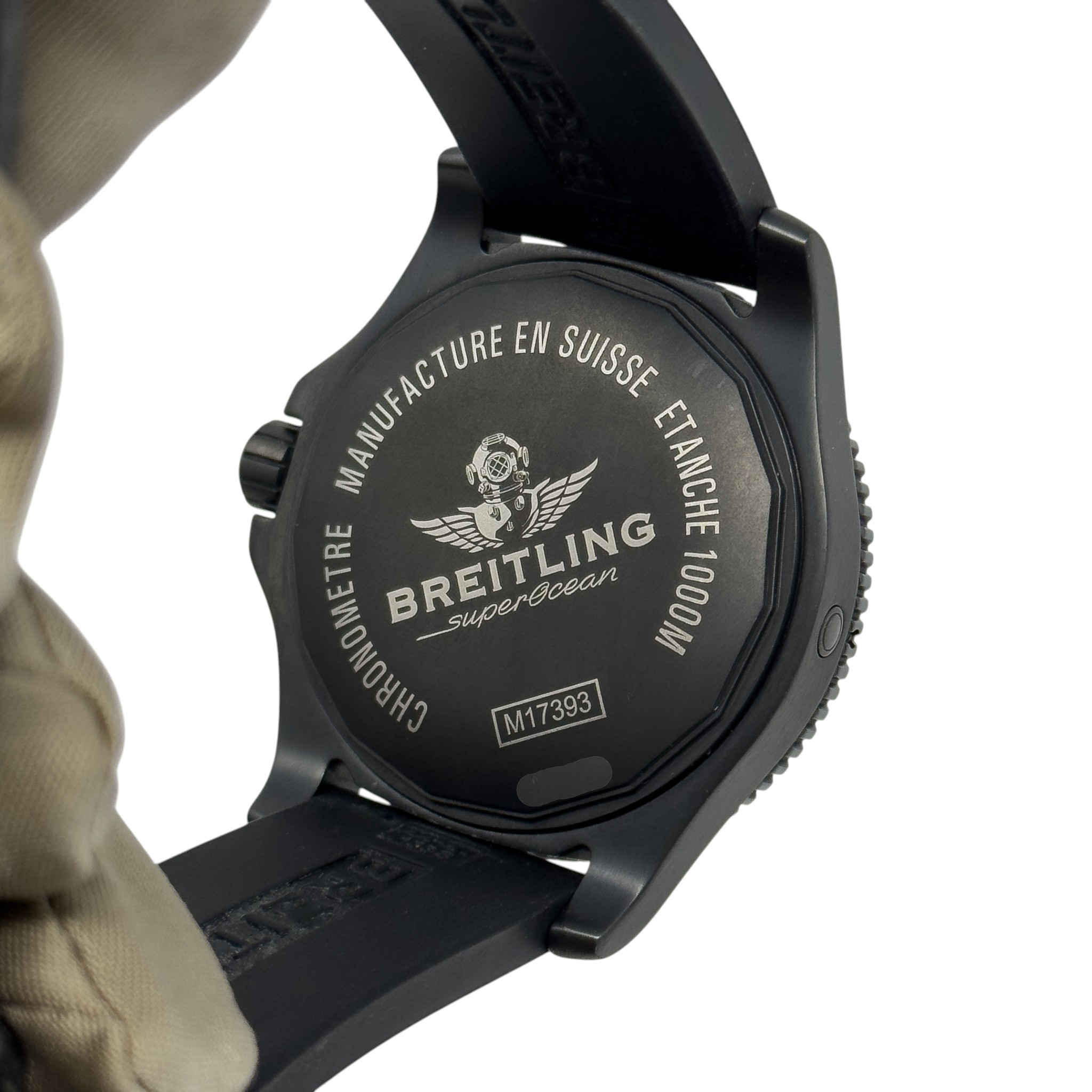 Back of a black Breitling Superocean watch case with engraved logo, model number M17393, and attached black rubber strap